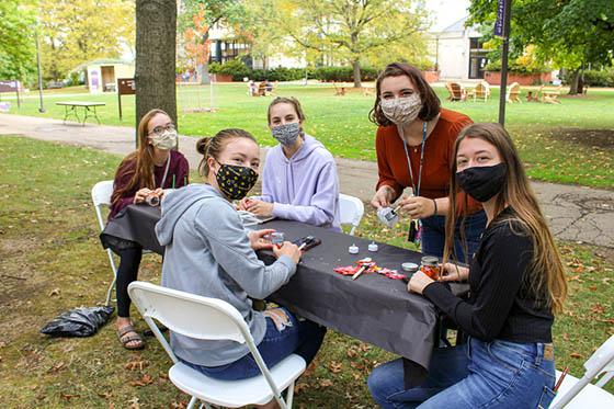 Photo of five masked students painting pumpkins outside in the 足球波胆平台 quad